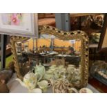 A CURVED LANDSCAPE ORIENTATED MIRROR WITH AN ORNATE GILT FRAME