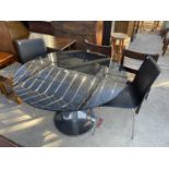 A RETRO BLACK GLASS TABLE, 43" DIAMETER AND TWO CHAIRS