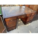 A 19TH CENTURY STYLE KNEEHOLE DESK WITH SEVEN DRAWERS AND INSET LEATHER TOP