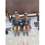 A RESIN LAUREL AND HARDY FIGURE SITTING ON A METAL BENCH