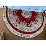 AN OVAL RED AND CREAM PATTERNED RUG