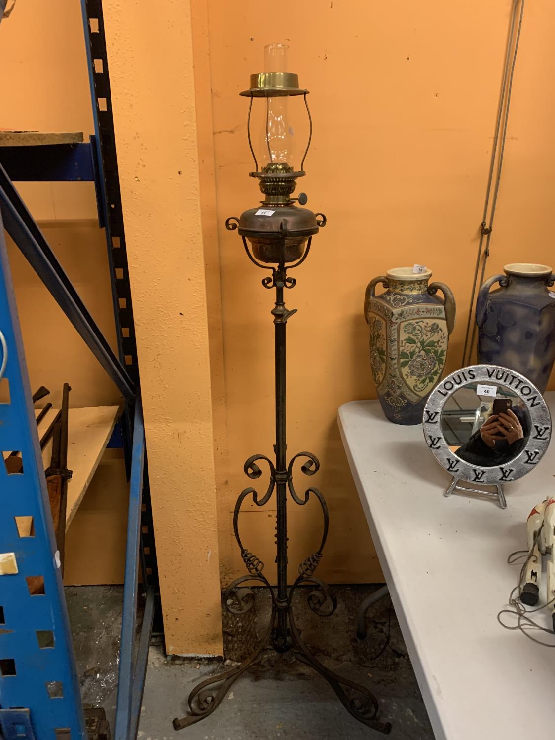 A VINTAGE OIL LAMP ON AN ADJUSTABLE METAL STAND