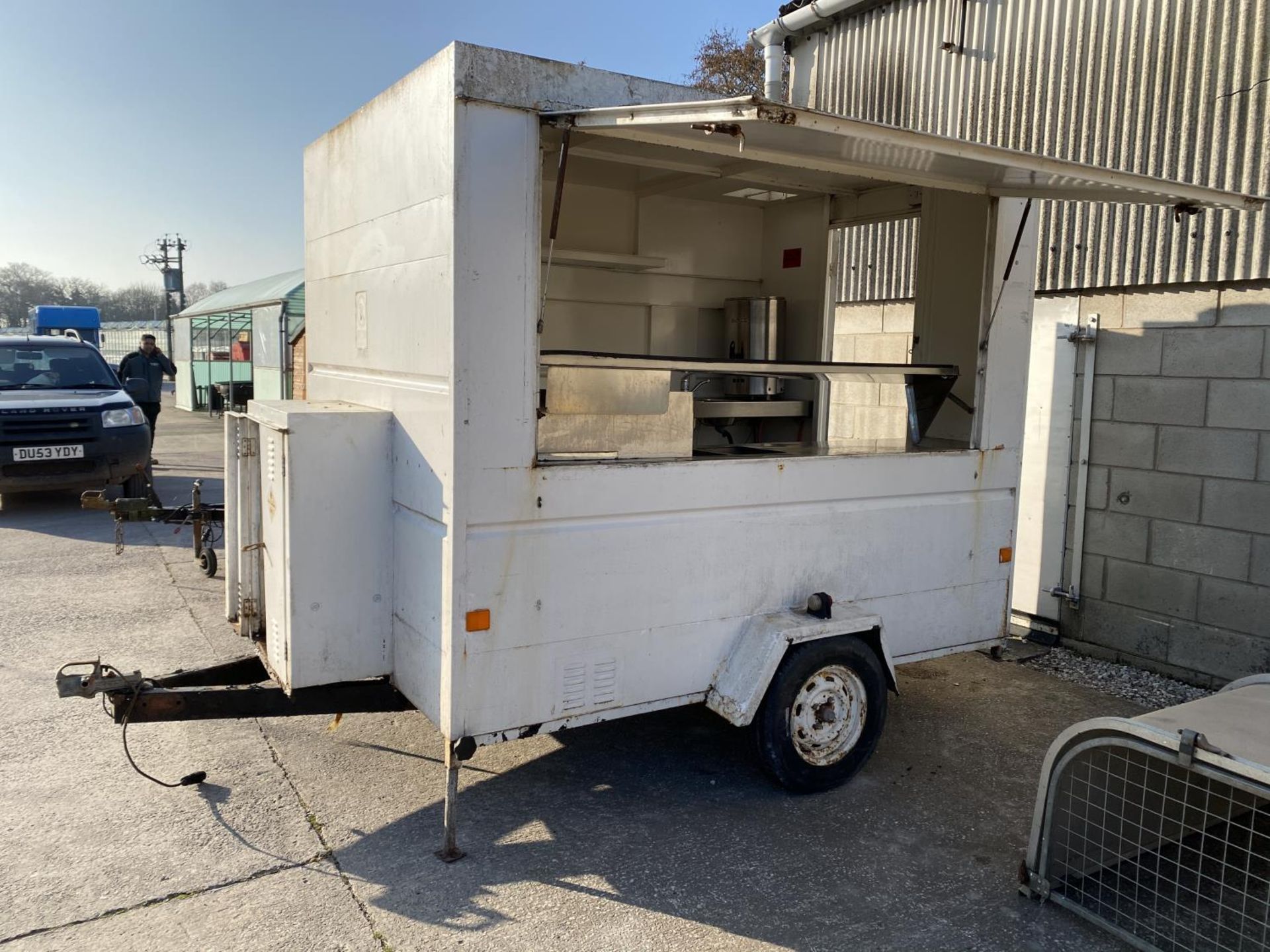 A CATERING TRAILER WITH LIFT UP SIDE. 8'3" LONG, 6' WIDE, DRAW BAR 3'3" LONG TOTAL LENGTH 11'6" WITH