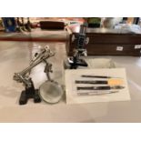 A SMALL MICROSCOPE WITH TOOLS AND A MAGNIFYING GLASS ON A STAND