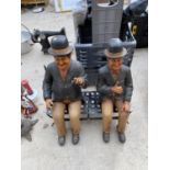 A RESIN LAUREL AND HARDY FIGURE SITTING ON A METAL BENCH