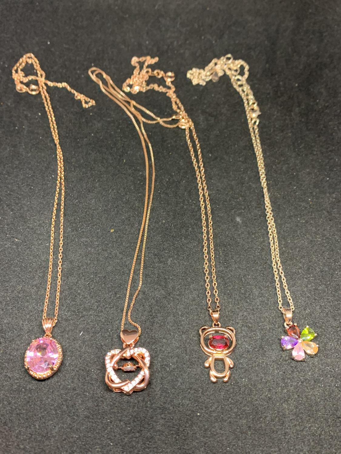 FOUR SILVER NECKLACES MARKED 925 WITH PENDANTS TO INCLUDE A TEDDY, FLOWER ETC WITH COLOURED STONES