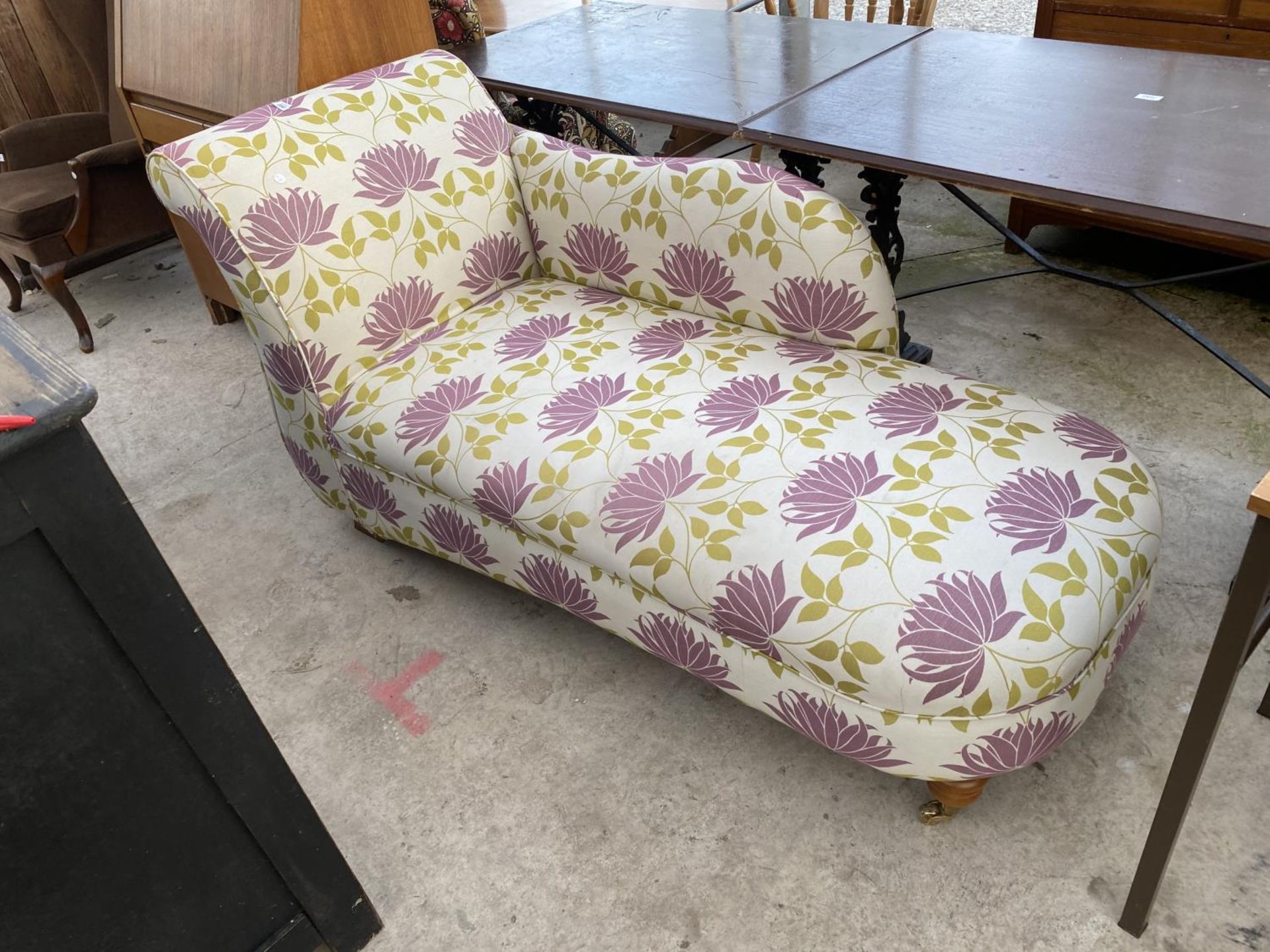 A MODERN FLORAL CHAISE LONGUE WITH TURNED LEGS AND BRASS CASTERS TO OPEN END