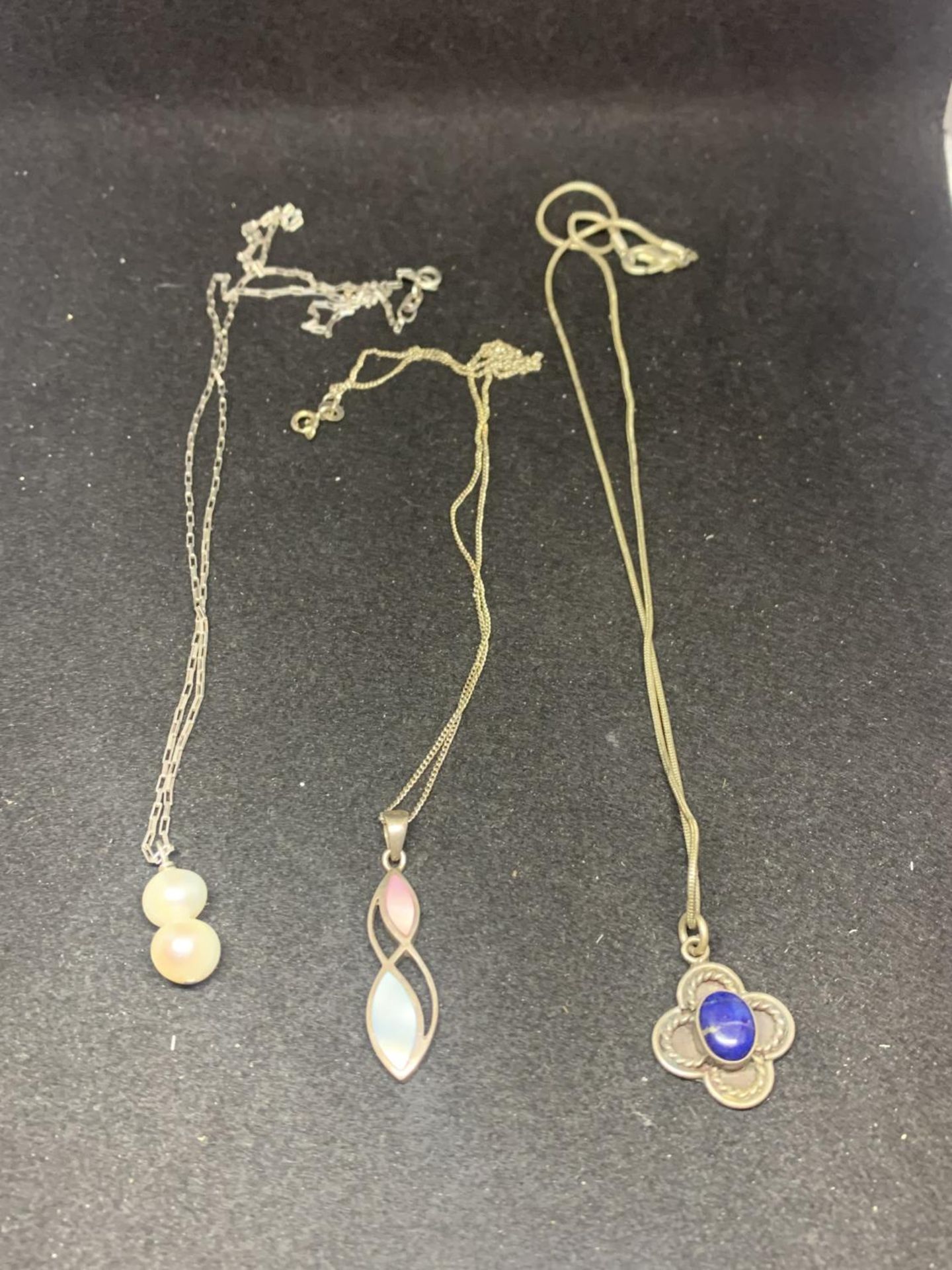 THREE SILVER NECKLACES WITH PENDANTS TO INCLUDE A BLUE STONE FLOWER DESIGN, PEARLS ETC