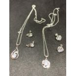 TWO SILVER NECKLACES WITH PENDANTS TO INCLUDE CLEAR STONE FLOWER AND TWIST BOTH WITH MATCHING