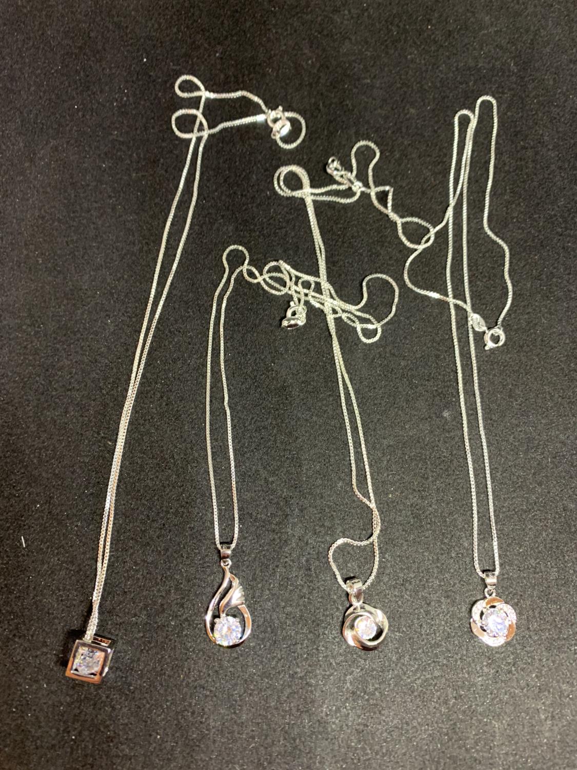FOUR SILVER NECKLACES WITH PENDANTS TO INCLUDE A CUBE, TWIST, FLOWER ETC WITH CLEAR STONES