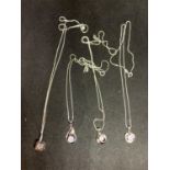 FOUR SILVER NECKLACES WITH PENDANTS TO INCLUDE A CUBE, TWIST, FLOWER ETC WITH CLEAR STONES