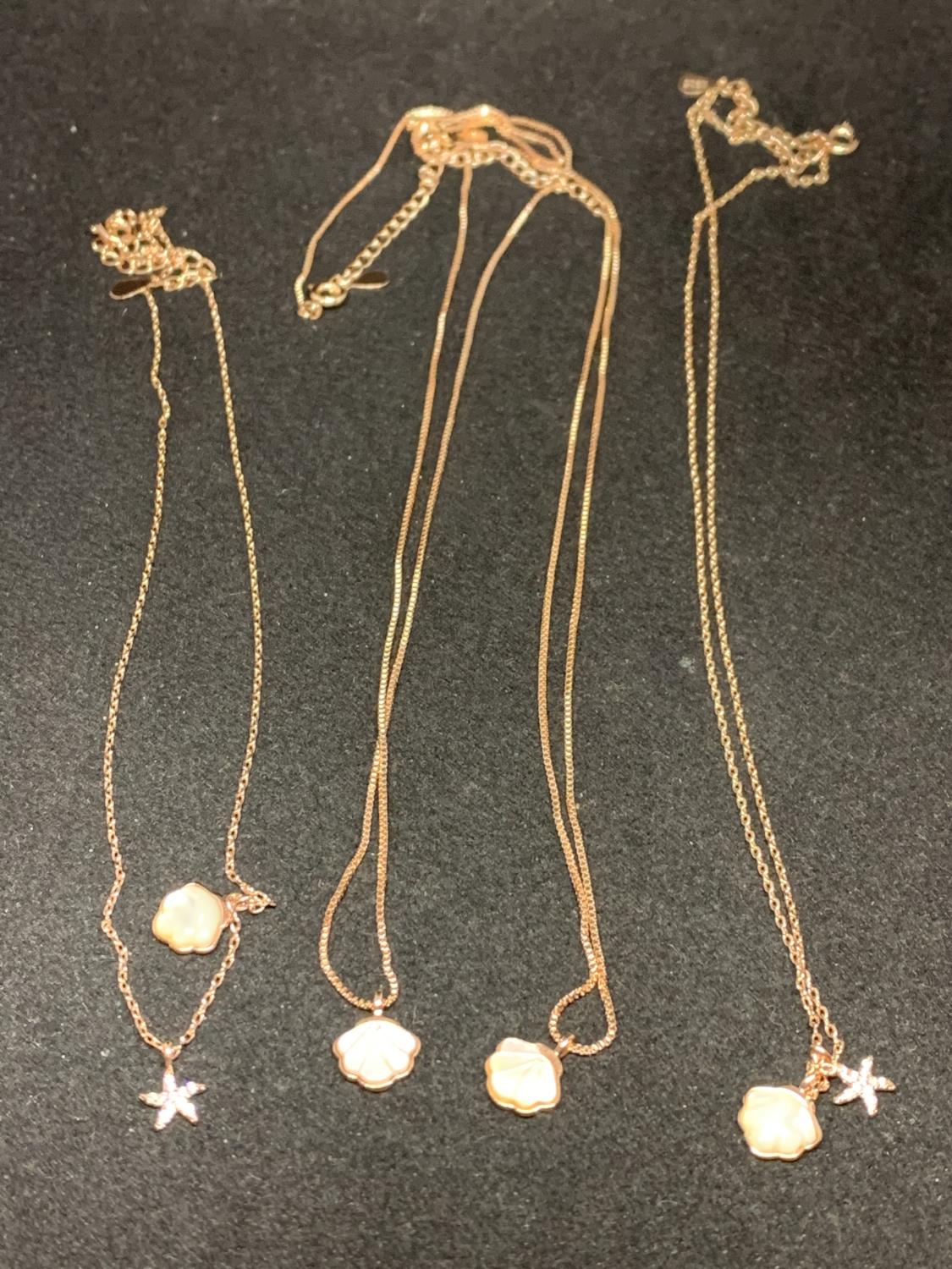 FOUR SILVER NECKLACES MARKED 925 WITH ROSE COLOURED GILDING WITH SHELL AND STAR FISH PENDANTS