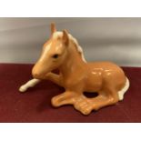 A BESWICK PALAMINO FOAL LYING DOWN