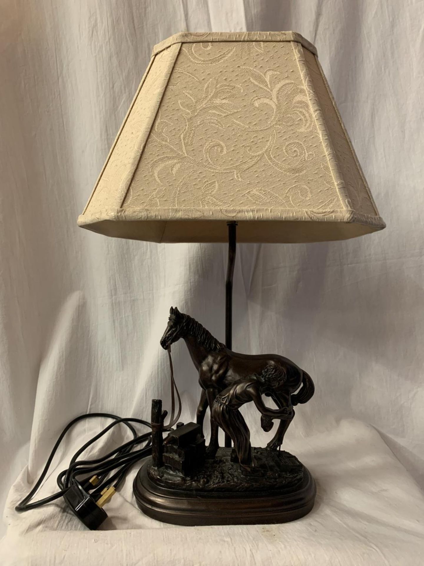 A HIGHLY DECORATIVE TABLE LAMP IN THE FORM OF A HORSE AND BLACKSMITH AT WORK H: TO BULB BASE 38CM