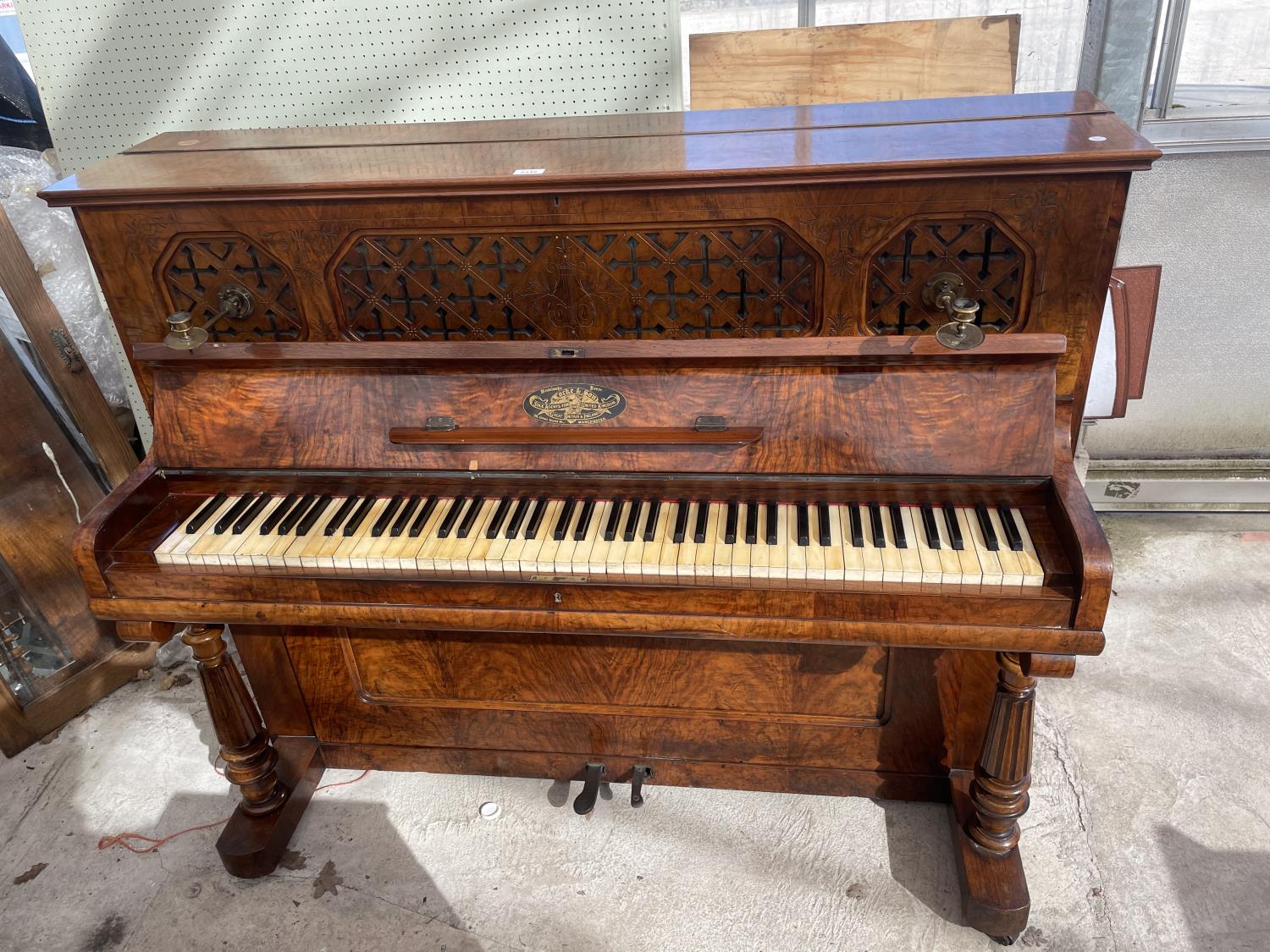 A WALNUT CASED OVERSPRUNG PIANO BEARING LOCKE & CO MANCHESTER