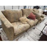 A VICTORIAN STYLE SPRUNG AND UPHOLSTERED THREE SEATER SETTEE AND CHAIR ON TURNED LEGS WITH BRASS