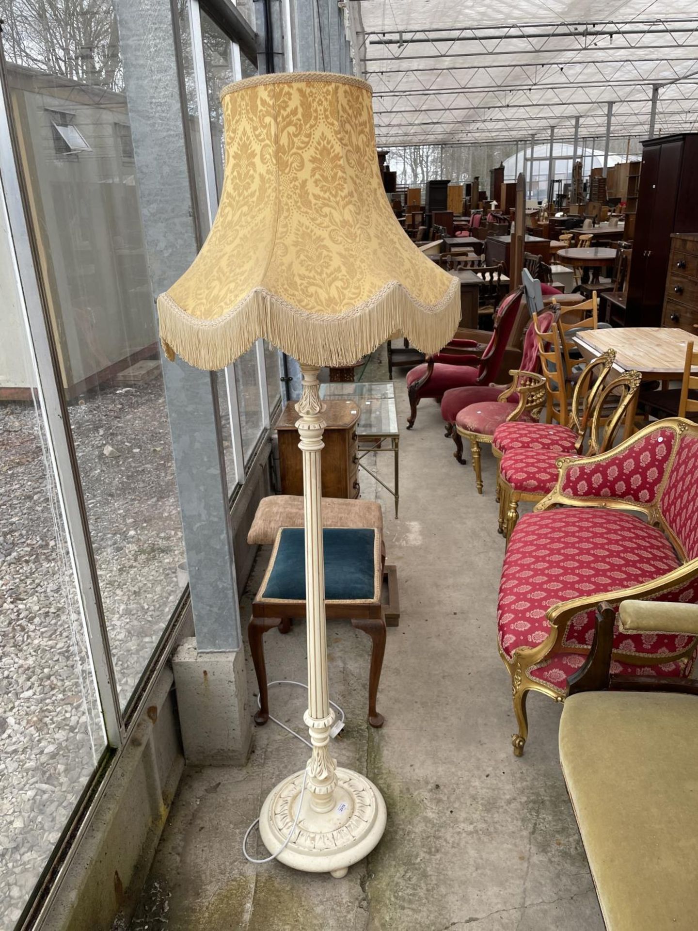 A CREAM AND GILT STANDARD LAMP COMPLETE WITH SHADE