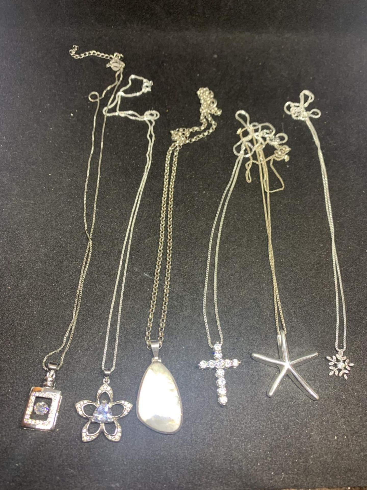 SIX SILVER NECKLACES WITH PENDANTS TO INCLUDE CLEAR STONE FLOWERS, CROSS ETC