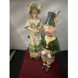 A GERMAN BISC FIGURINE IN THE FORM OF A LADY AND A DECANTER IN THE FORM OF A GERMAN BOY (HAT A/F)