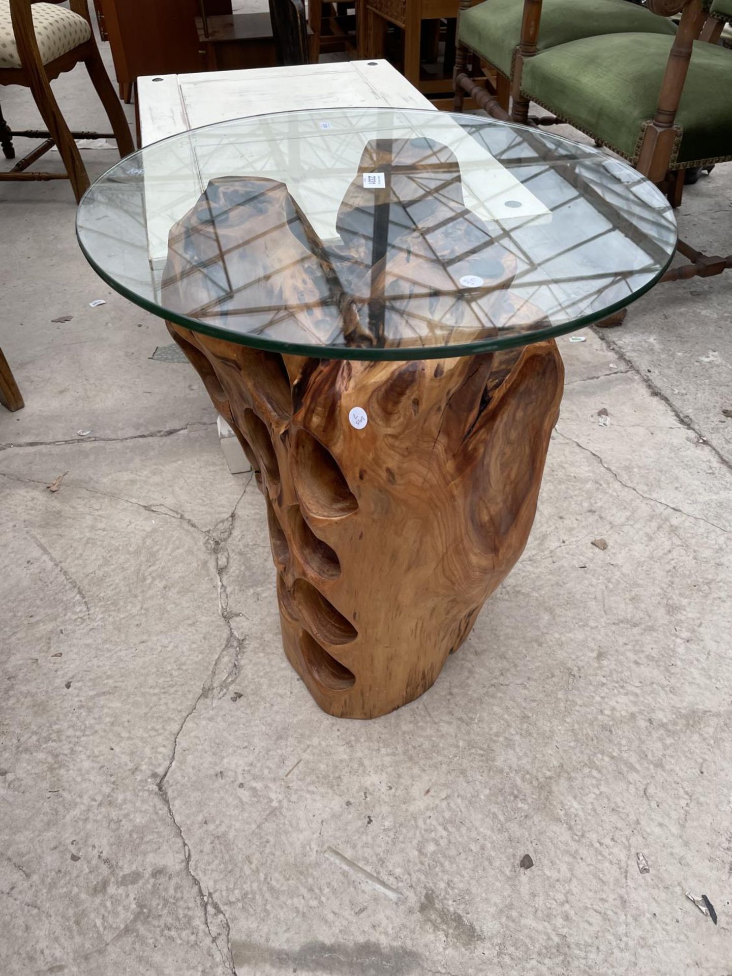 A WINE TABLE WITH GLASS TOP, MADE FROM A LARGE TREE ROOT INCORPORATING A 12 BOTTLE WINE HOLDER,