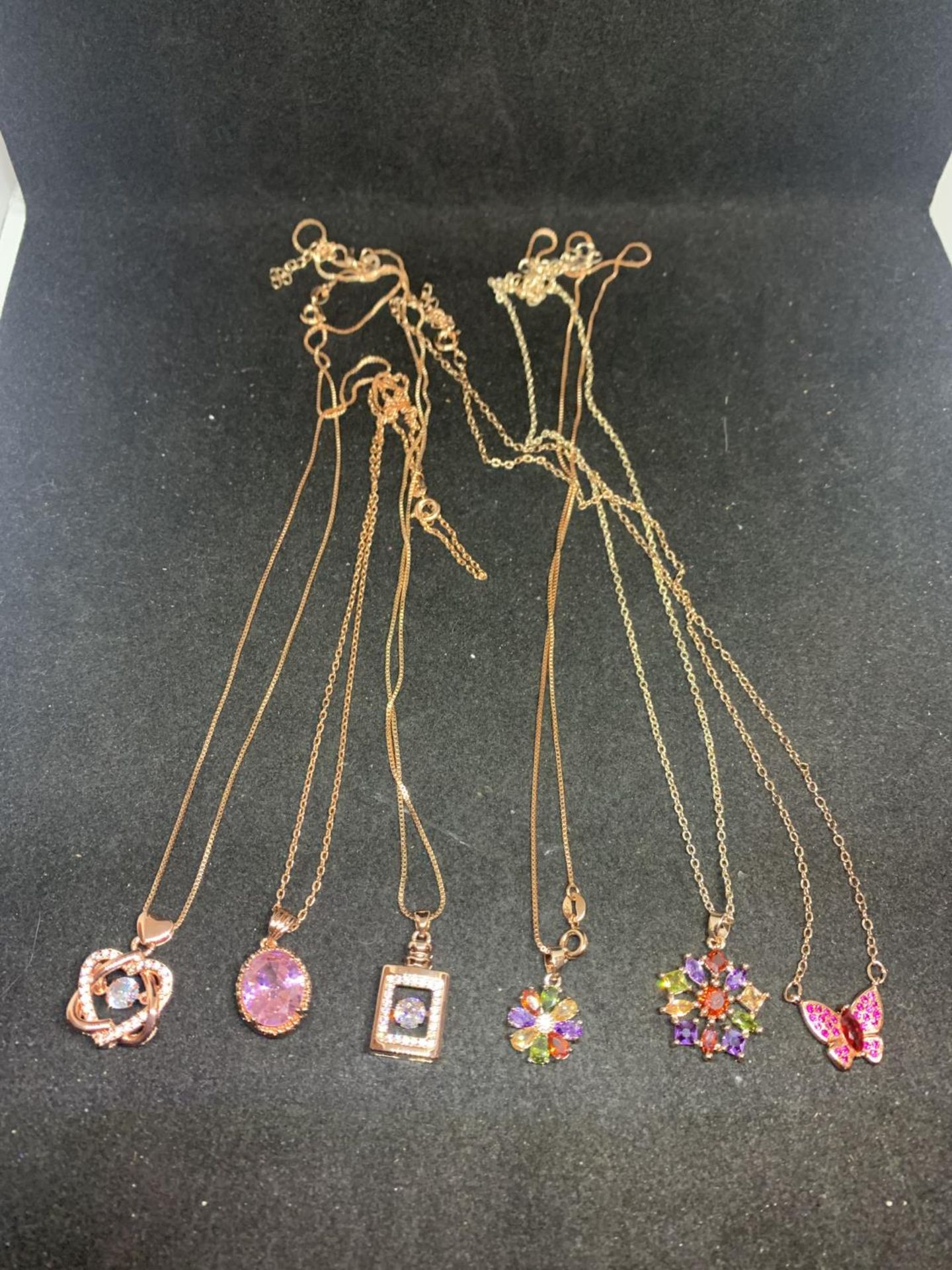 SIX SILVER NECKLACES WITH ROSE GILT AND COLOURED STONE PENDANTS