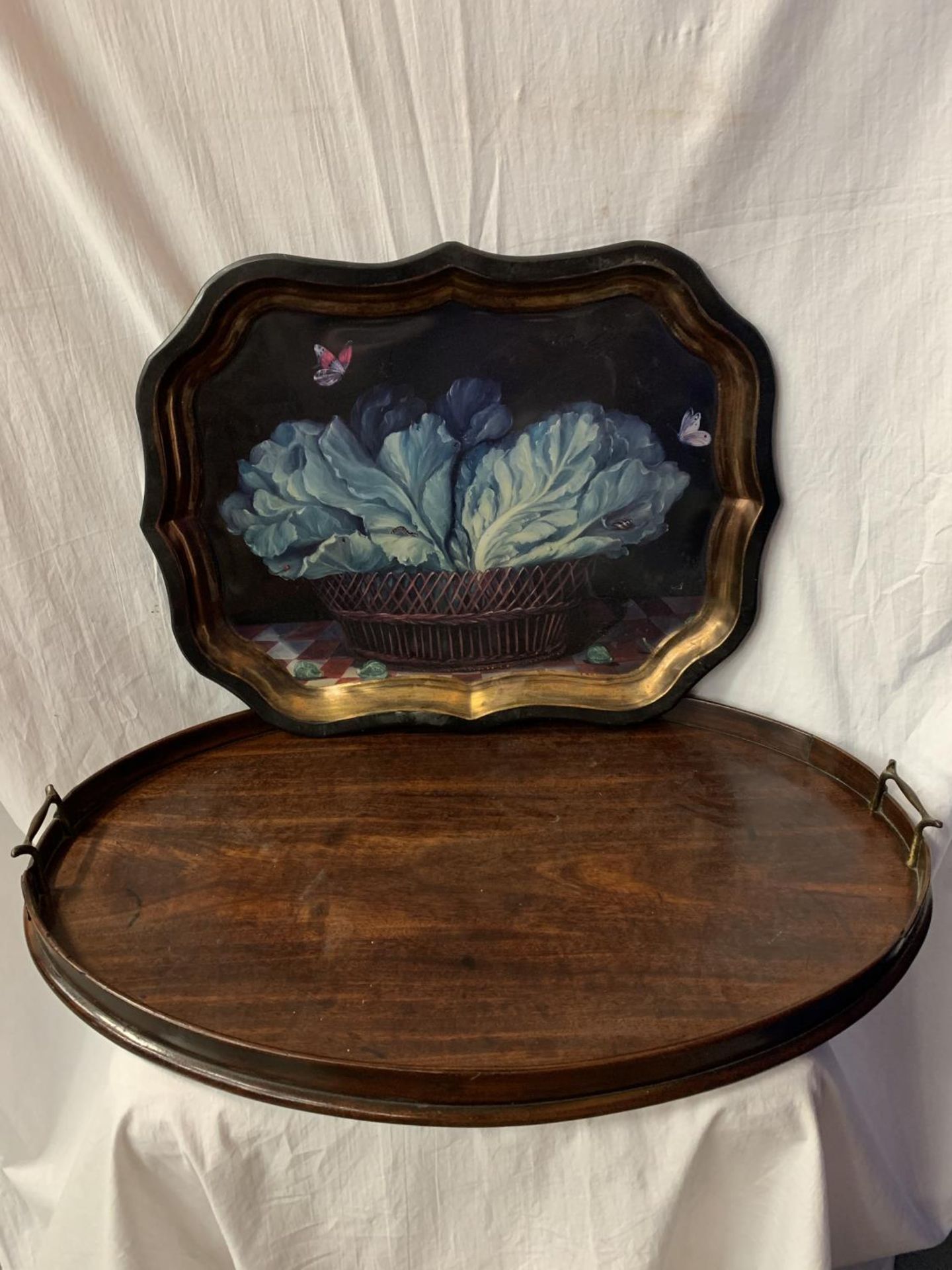 A LARGE WOODEN OVAL BUTLERS TRAY AND A DECORATIVE TIN TRAY WITH VEGETABLE BOWL DESIGN