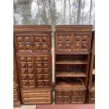 A PAIR OF SPANISH WALNUT HEAVILY PANELED WALL UNITS WITH TWO CUPBOARDS AND THREE DRAWERS TO THE BASE