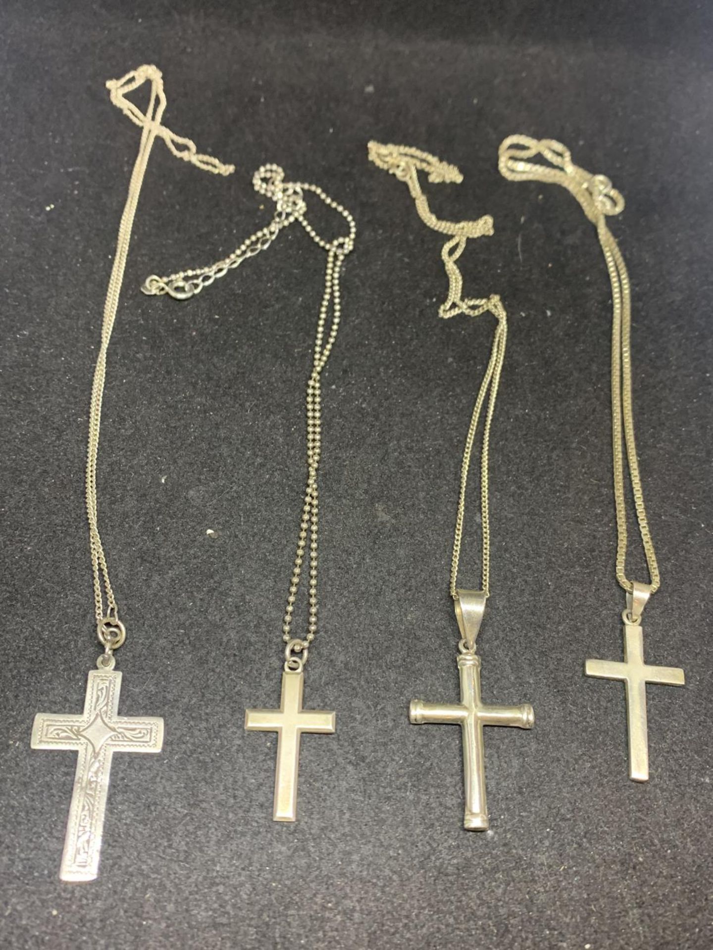 FOUR SILVER CHAINS WITH VARIOUS CROSS PENDANTS
