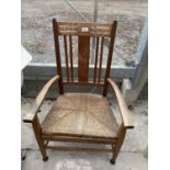 AN ART NOUVEAU OAK FRAMED LOW ARM CHAIR WITH AN INLAID CLOVER LEAF AND A RUSH SEAT
