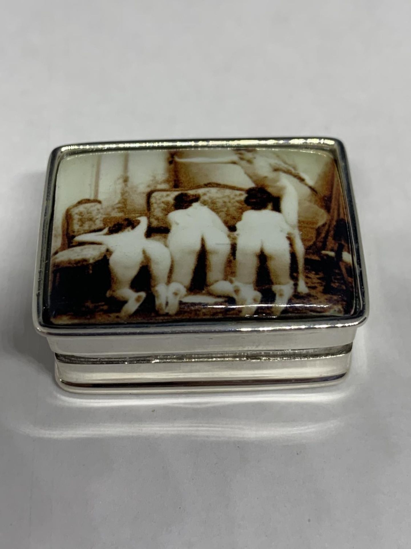 A SILVER PILL BOX WITH AN ENAMEL EROTIC DESIGN ON THE LID