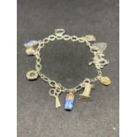 A SILVER CHARM BRACLET WITH ELEVEN CHARMS AND A HEART CLASP TO INCLUDE SCISSORS, CRADLE, HORSE AND