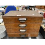 A VINTAGE WOODEN FOUR DRAWER MINIATURE FILING CABINET