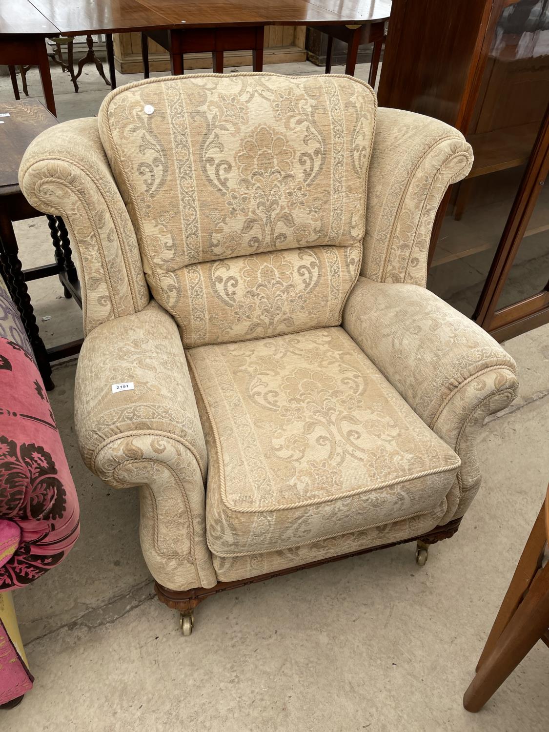 A WING BACK ARMCHAIR OM MAHOGANY SUPPORTS WITH BRASS CASTERS