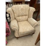 A WING BACK ARMCHAIR OM MAHOGANY SUPPORTS WITH BRASS CASTERS