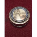 A WHITE METAL (BELIEVED SILVER) PILL BOX WITH ENAMELED GIRL WITH BIRD OF PREY DECORATION