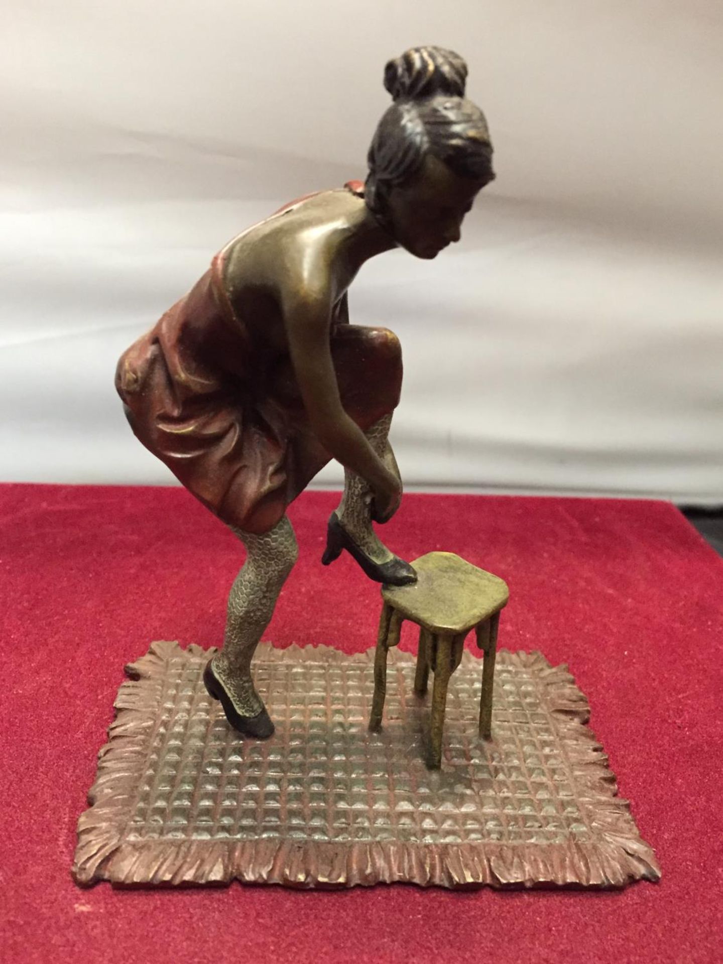 A BERGMAN STYLE COLD PAINTED FIGURINE OF A LADY WITH HER FOOT ON A STOOL HEIGHT APPROXIMATELY 12CM