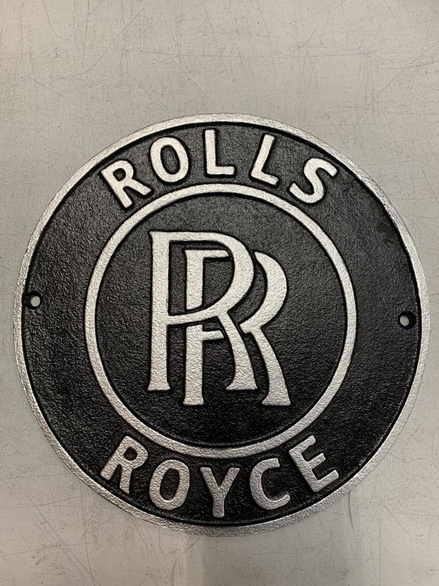 A CIRCULAR CAST METAL ROLLS ROYCE SIGN 24CM