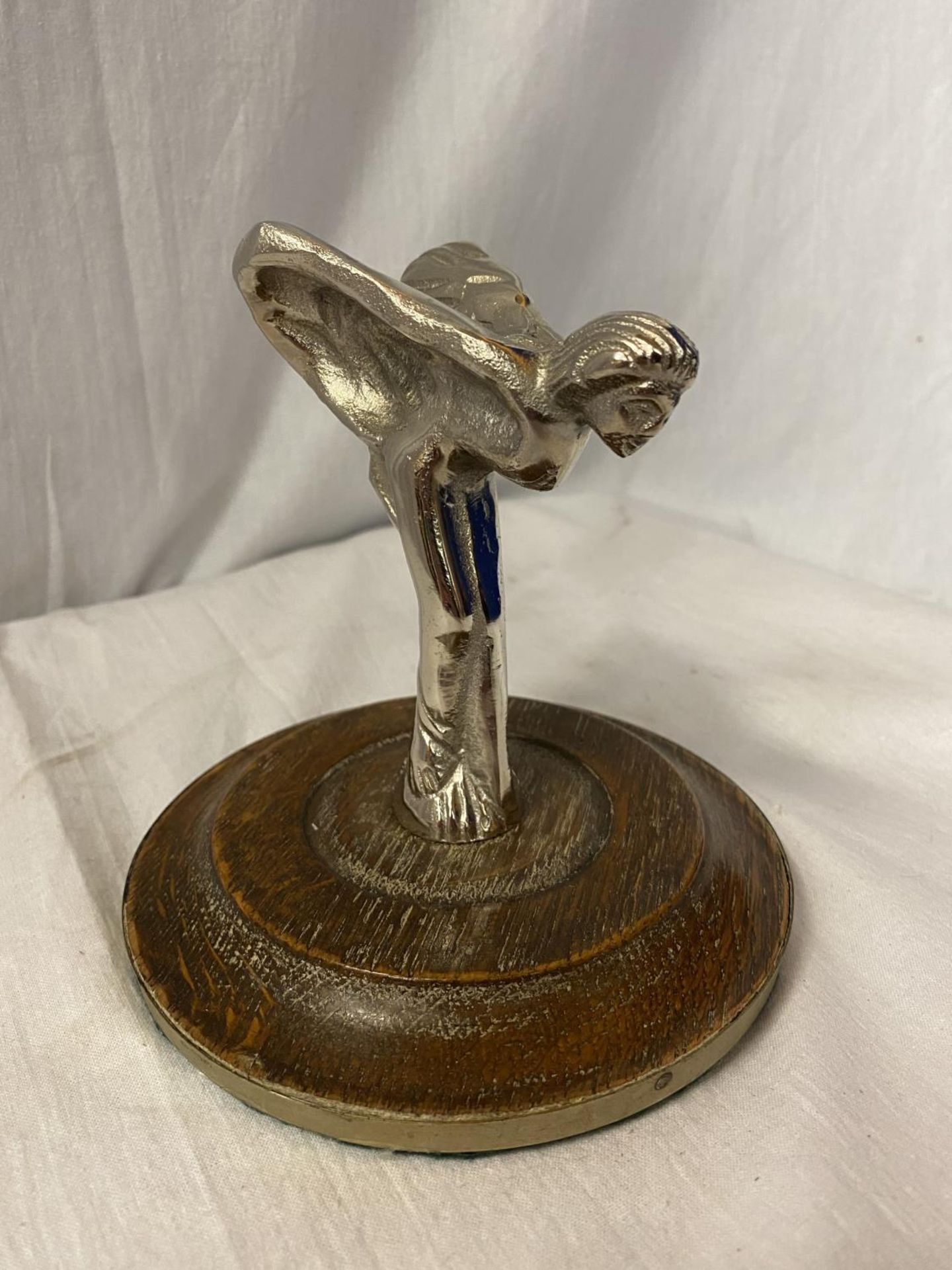 A WHITE METAL FLYING LADY MASCOT MOUNTED ON AN OAK PLINTH H: APPROX 13.5CM