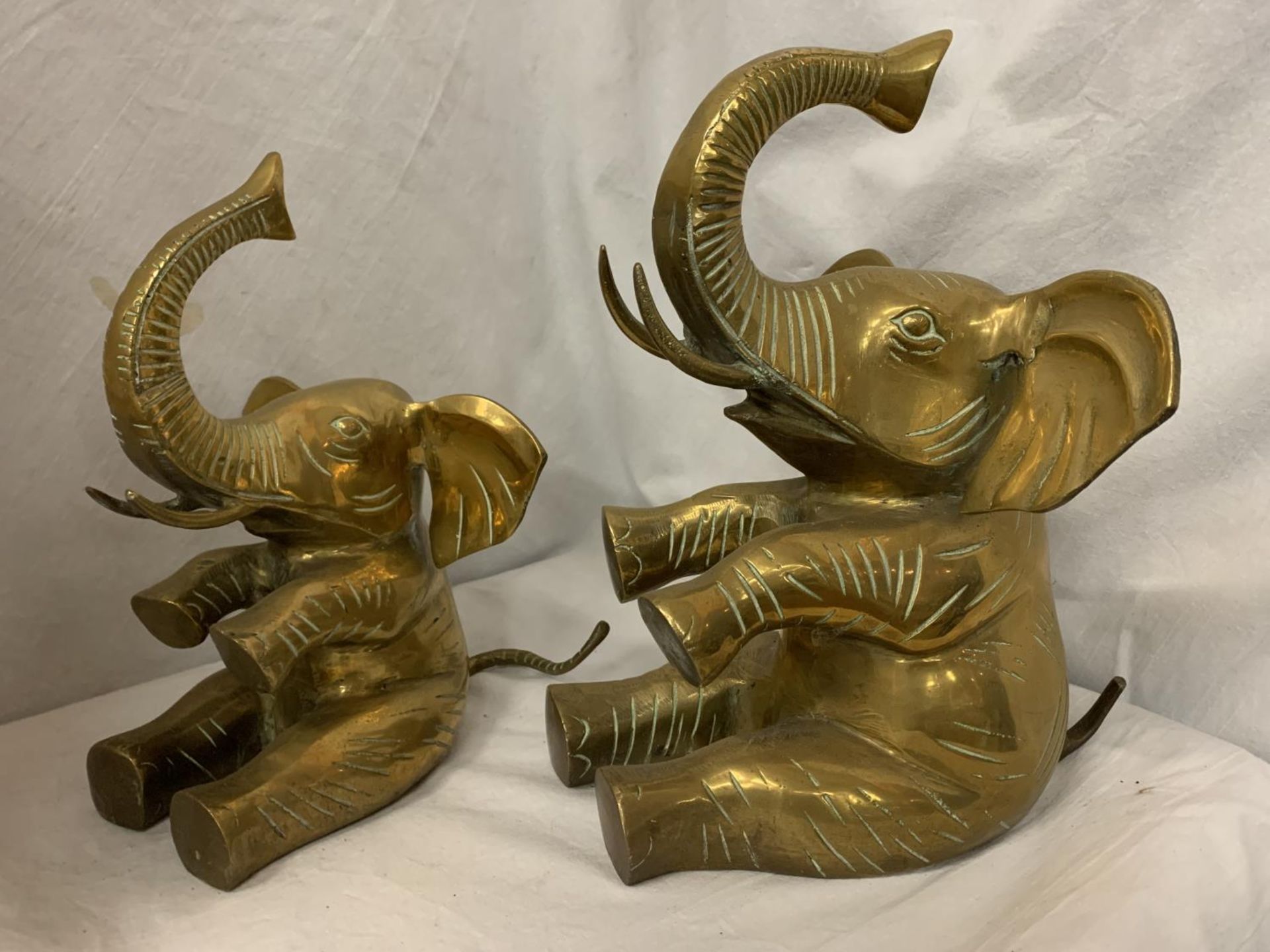 A PAIR OF SEATED BRASS ELEPHANTS H:31 CM AND 25CM