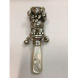 A SILVER MARKED 925 BABIES RATTLE WITH MOTHER OF PEARL HANDLE IN THE DESIGN OF A TEDDY BEAR WITH