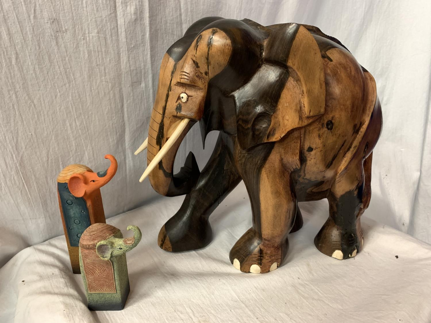 A LARGE CARVED HEAVY HARD WOOD ELEPHANT (H: APPROX. 30CM) AND TWO CERAMIC ELEPHANT ITEMS