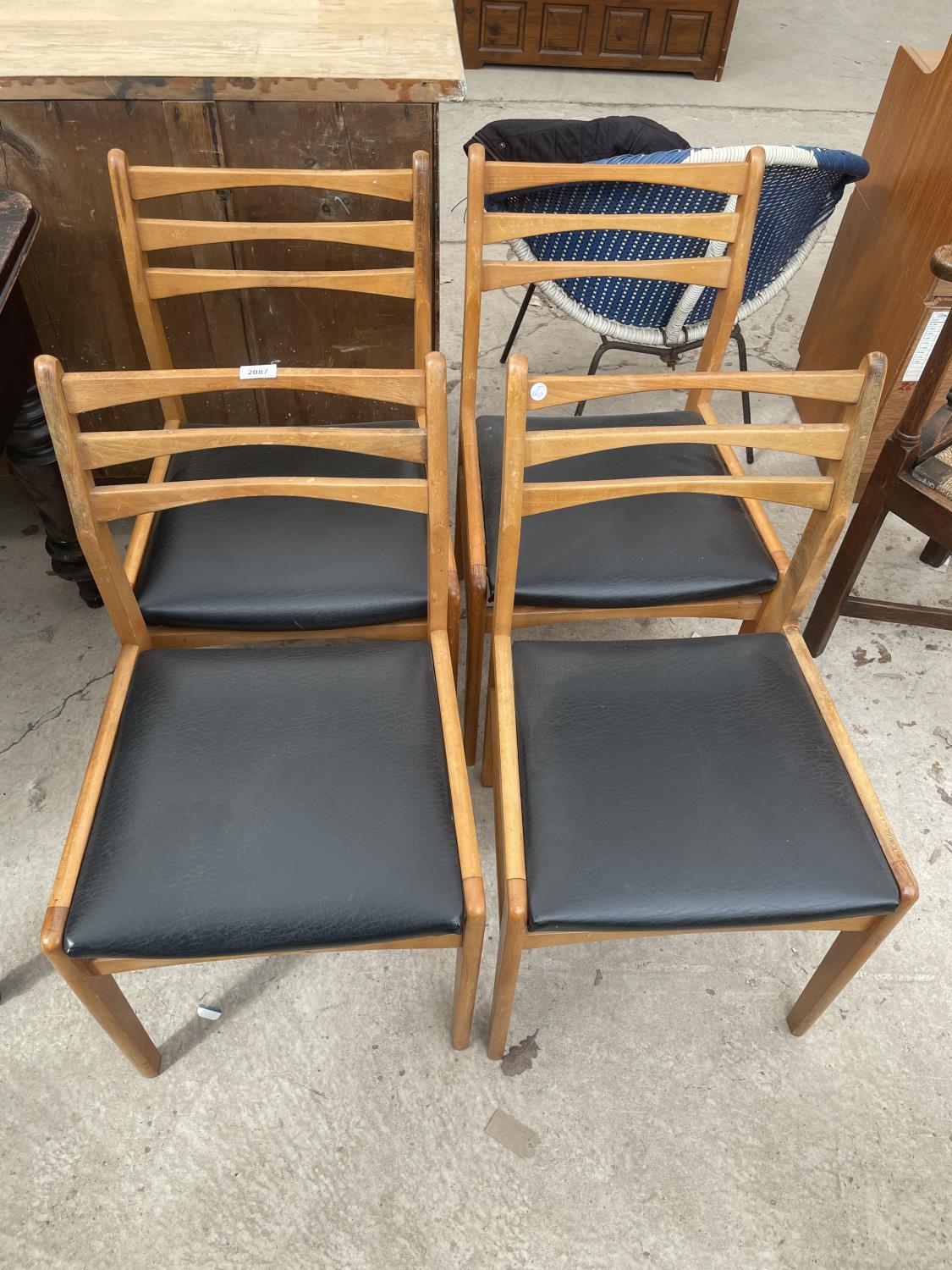 A SET OF FOUR RETRO TEAK PARTIAL LADDERBACK DINING CHAIRS WITH BLACK REXENE SEATS