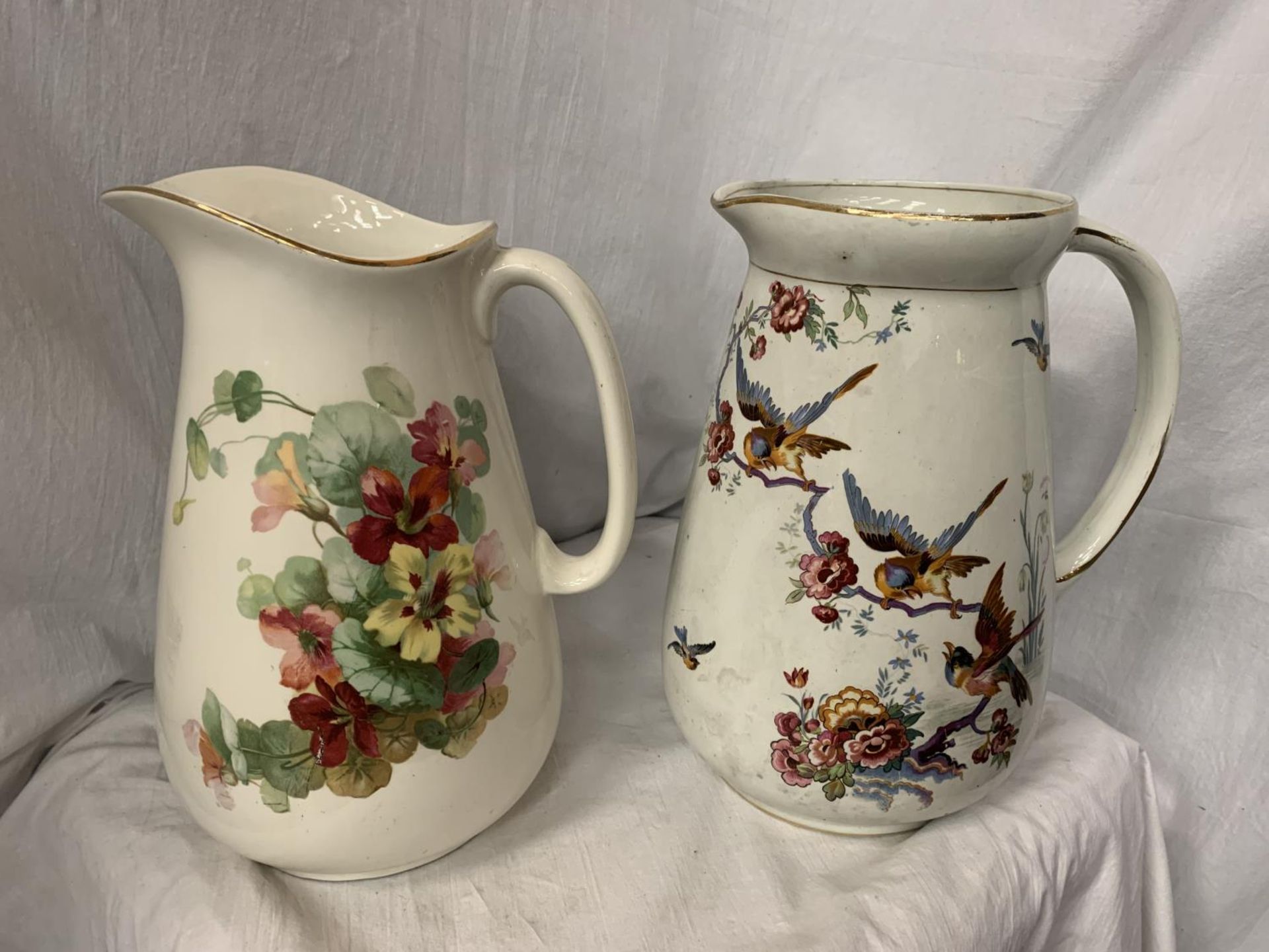 TWO LARGE CERAMIC JUGS ONE WITH FLORAL DECORATION, THE OTHER PEARL POTTERY WITH AVIAN DESIGN H: 31CM