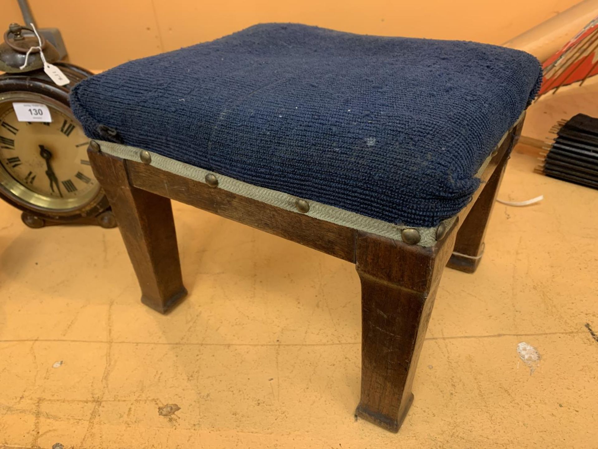 A SMALL FOUR LEGGED BLUE UPHOLSTERED FOOTSTOOL