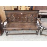 AN EARLY TWENTIETH CENTURY SETTLE WITH PANELLED BACK AND BARLEY TWIST LEGS 61 INCHES WIDE
