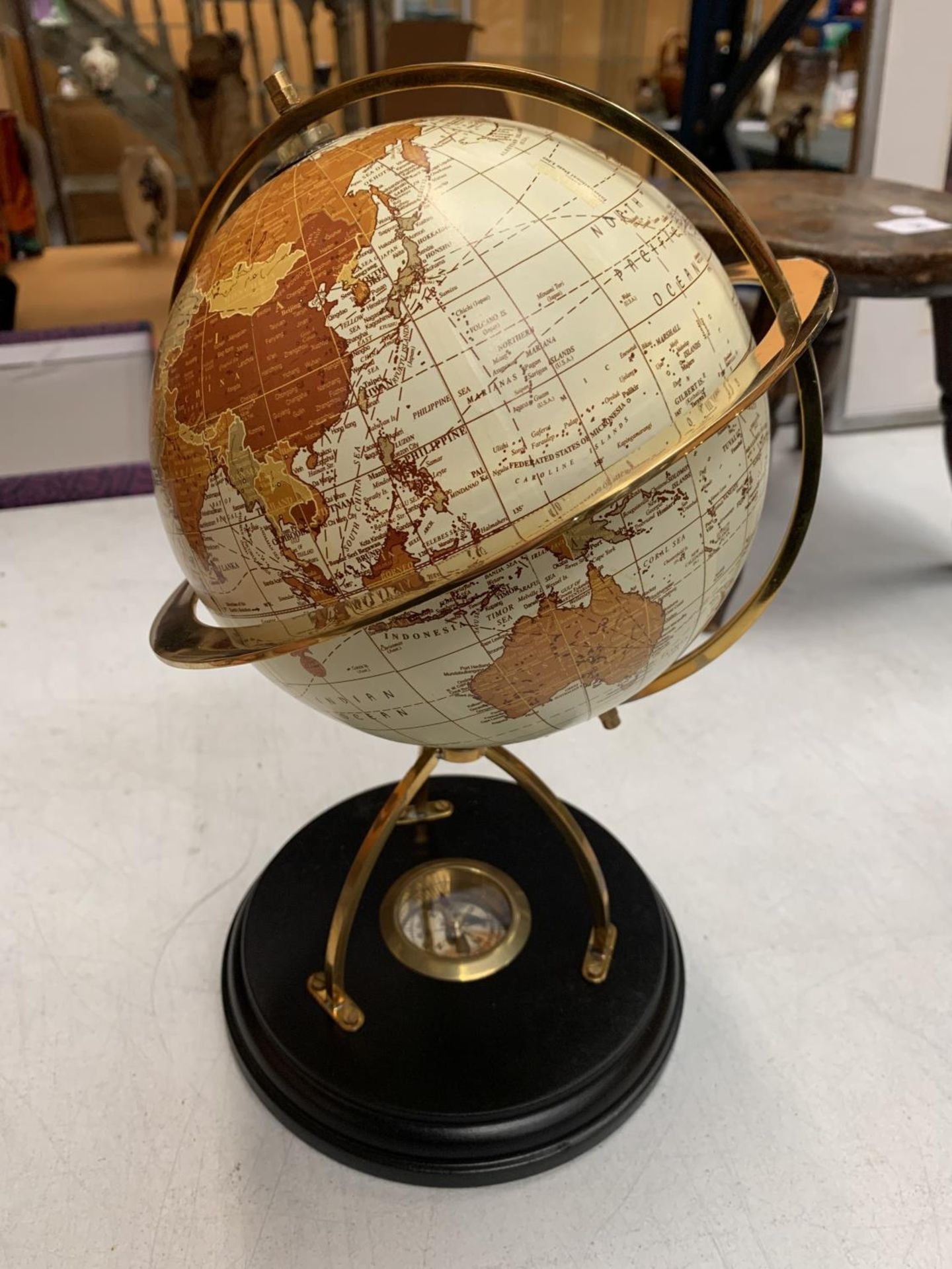 A DECORATIVE DESK GLOBE WITH BRASS DETAIL AND INTEGRATED COMPASS IN THE BASE H: APPROXIMATELY 31CM