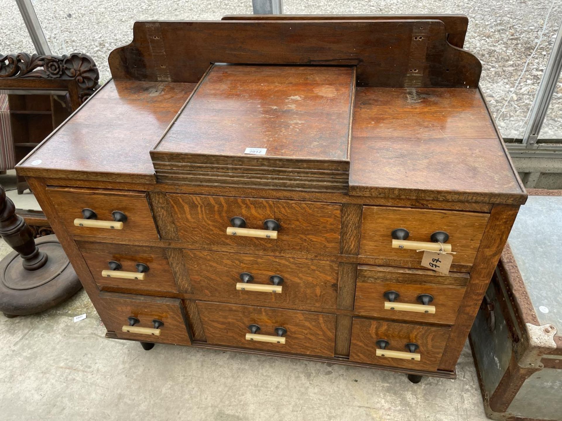 AN EARLY 20TH CENTURY OAK DRESSING CHEST ENCLOSING NINE DRAWERS
