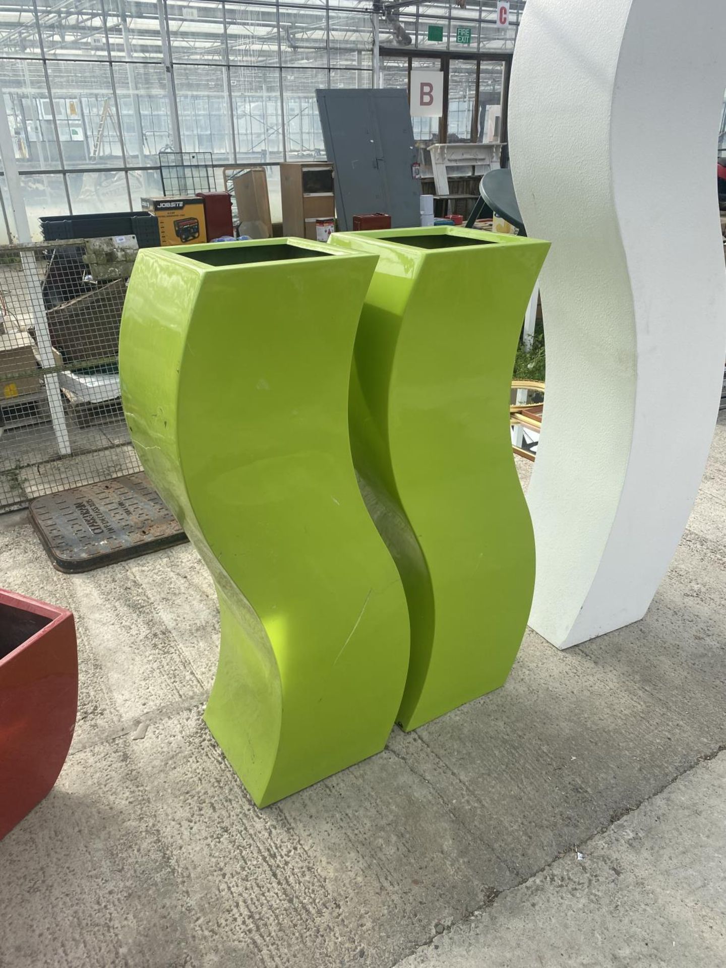A PAIR OF UNUSUAL TALL AND CURVED DECORATIVE GREEN PLASTIC PLANTERS (H:120CM)