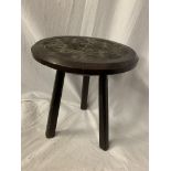A SMALL THREE LEGGED HARD WOOD STOOL WITH CARVING TO THE SEAT H: 28.5CM