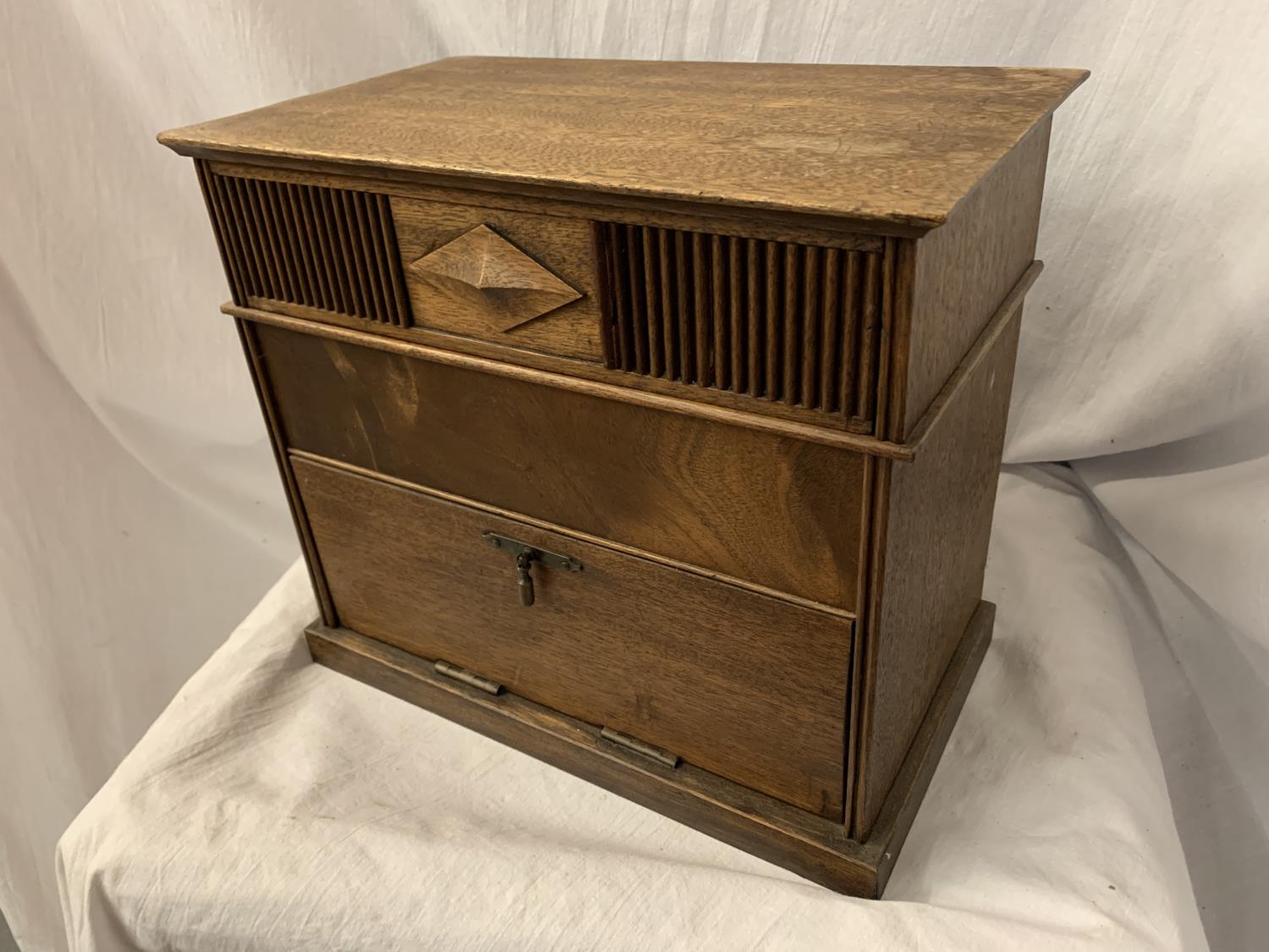 AN ARTS AND CRAFTS STYLE OAK TABLE TOP BOX ENCLOSING THREE DIVISIONS AND A DROP LEAF CUPBOARD 28CM X